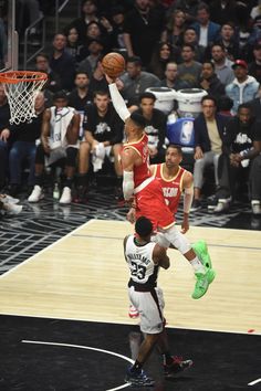 a basketball player jumping up to dunk the ball in front of an audience at a game