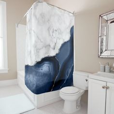 a white toilet sitting next to a bathroom sink under a shower curtain with black and white marble on it