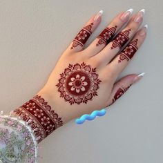 a woman's hand with henna on her left arm and hands painted red