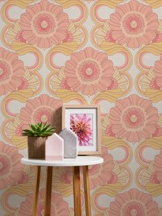 a table with a potted plant on top of it next to a wallpaper