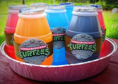 four different colored drinks in a metal bowl