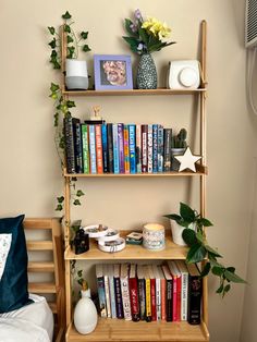 a bookshelf filled with lots of books next to a plant and vases