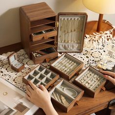 a woman is looking at jewelry in her wooden box on the table next to it