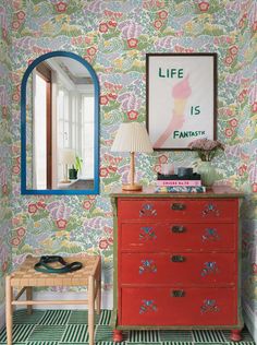 a red dresser sitting next to a mirror on top of a wall