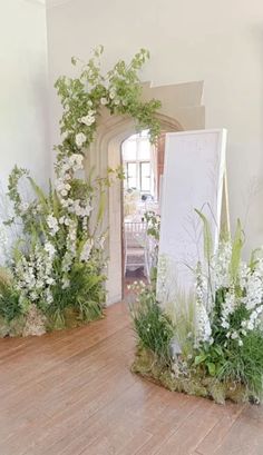 an arrangement of flowers and greenery on display in a room