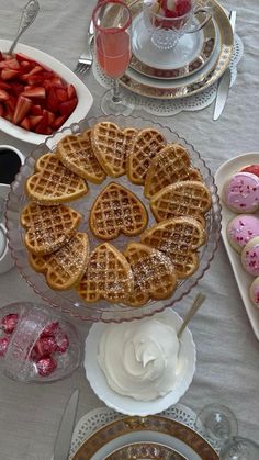 a table topped with waffles covered in icing next to plates of strawberries