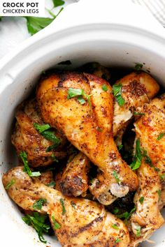 a white bowl filled with cooked chicken and garnished with parsley on top