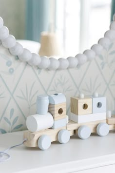 a wooden toy train sitting on top of a white dresser next to a blue and white wall