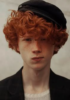 a young man with red hair wearing a black hat