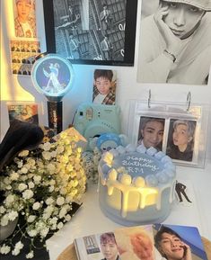 a birthday cake sitting on top of a table next to pictures and flowers in vases