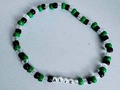 a green and white beaded bracelet with the word babe written in small letters on it