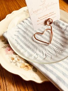 a heart shaped napkin holder sitting on top of a plate next to a place card