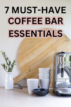 there is a coffee bar with cups on the counter and a wooden board behind it that says 7 must - have coffee bar essentials