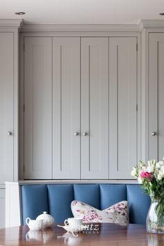 a vase with flowers sitting on top of a wooden table next to a blue bench