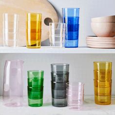 several different colored glasses sitting on top of a shelf