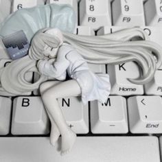 a white doll laying on top of a computer keyboard