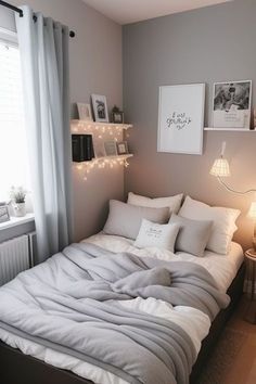 a bed with white sheets and pillows in a bedroom next to a window filled with pictures