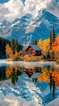 a cabin sits on the shore of a lake with mountains in the background and clouds in the sky