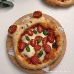 a pizza with toppings on it sitting on top of a wooden plate next to another pizza