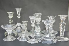 an assortment of glass candlesticks and vases on a black tableclothed surface