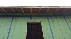 an open window on the side of a green building with scaffolding around it