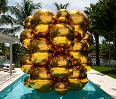 a large bunch of shiny balls sitting on top of a pool next to palm trees