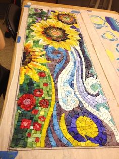 a table that has some kind of mosaic on it with flowers and leaves painted on it