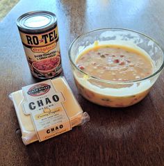 a bowl of soup next to a can of cheetos on a wooden table