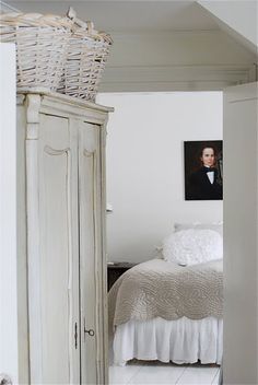 a bedroom with a white bed and an armoire