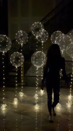 a woman walking down a hallway covered in lots of white balls and string lights at night