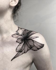 a black and white photo of a woman's chest with a flower tattoo on it