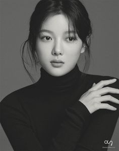 a black and white photo of a woman with her hands on her chest, wearing a turtle neck sweater