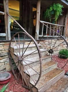 an old wooden wagon wheel sitting on the side of a stone building next to flowers