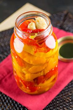 a jar filled with pickles on top of a pink napkin