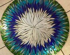 a blue and green glass plate sitting on top of a tile floor next to a tiled floor