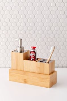 a wooden holder with toothbrushes, soap and lotion in it on a white table