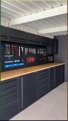 an organized garage with lots of tools hanging on the wall and cabinets in front of it