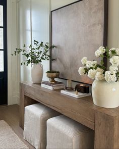 a table with two vases and flowers on it in front of a large mirror