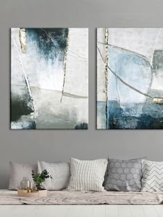 two paintings are hanging on the wall above a couch