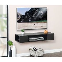 a flat screen tv mounted to the side of a wall next to a vase with flowers