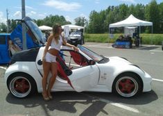 a woman sitting on top of a white sports car