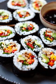 sushi is served on a plate with dipping sauce