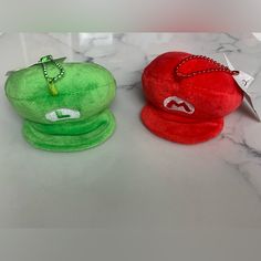 two hats sitting on top of a marble counter next to each other, one red and one green