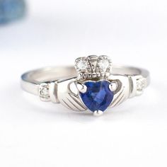 a cladder's ring with a heart shaped blue sapphire and two diamond accents