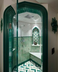 a bathroom with green and white tiles on the floor, shower stall and bathtub