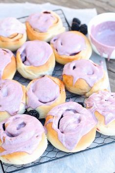 a bunch of doughnuts that are on a cooling rack and some blueberries