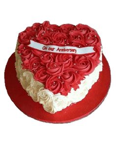 a heart shaped cake with red and white frosting roses on the top, sitting on a red plate