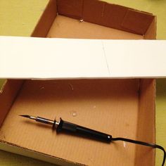 an open box with a pen in it on the floor next to a cardboard box