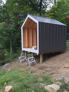 an outhouse built into the side of a hill with two chairs in front of it