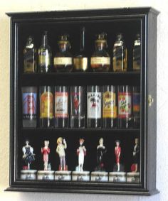 a display case filled with bottles and figurines on top of a white wall